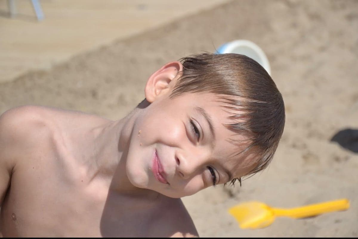 Carlos as a child, smiling on the beach