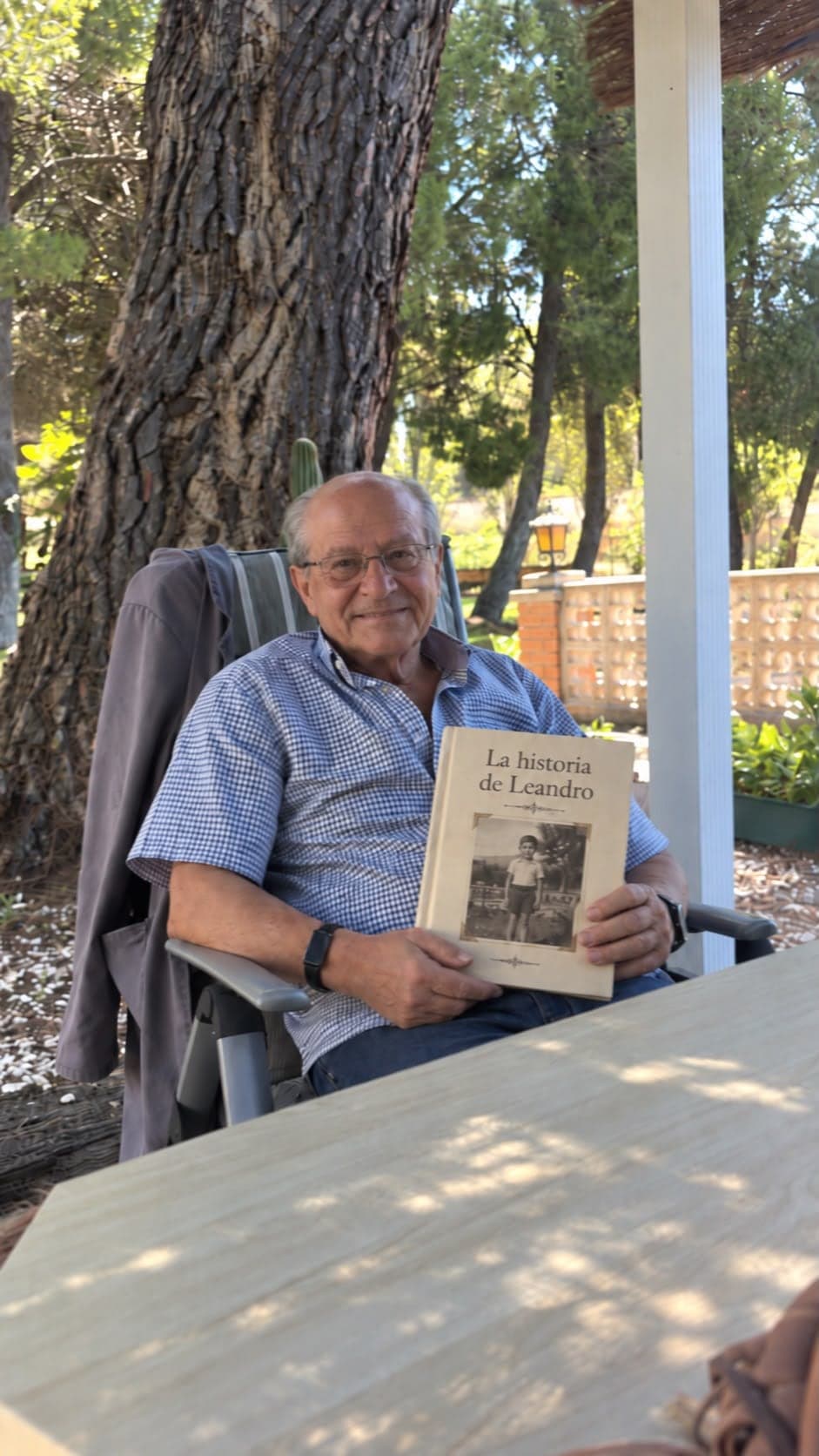 Leandro sitting in the garden, holding the printed book of his story