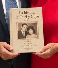 Puri and Goyo holding the book of their story, with an old photograph from their youth on the cover